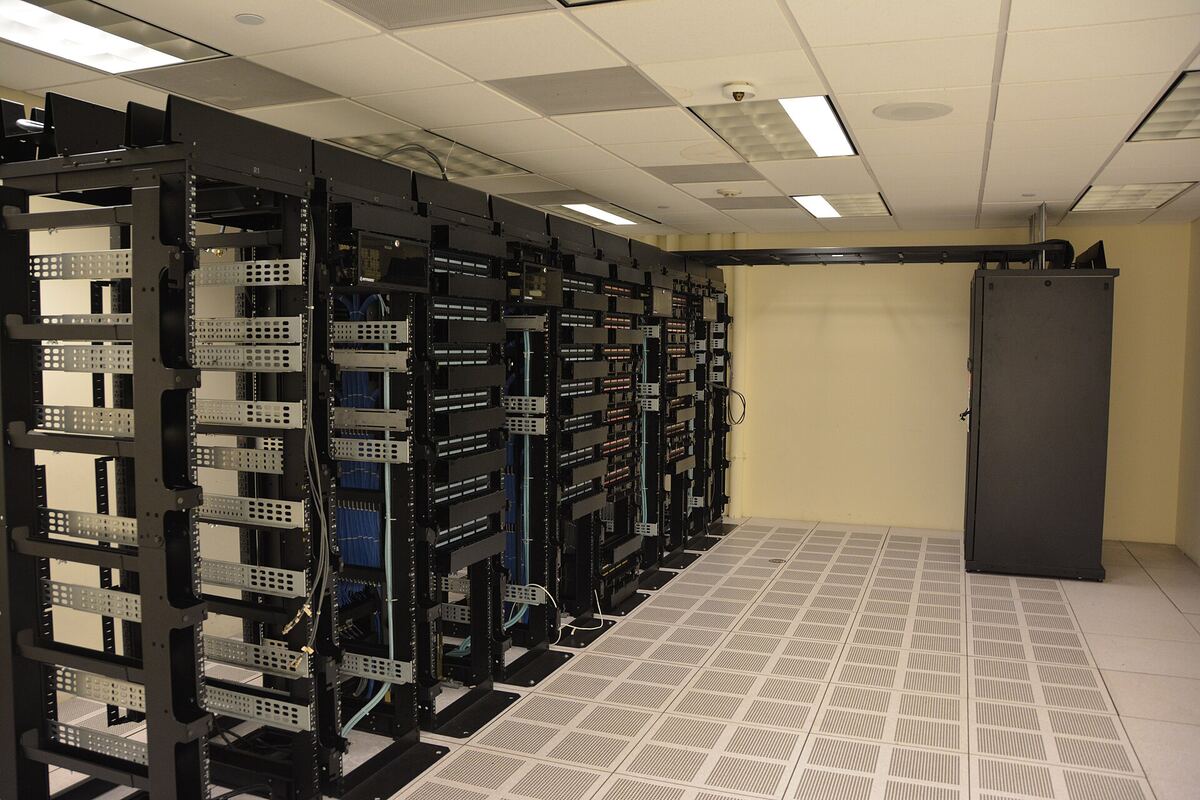 Open server racks in a data center, the hardware behind open-weight AI models like Kimi K3 and DeepSeek. Photo: Carl Lender, Wikimedia Commons, CC BY 2.0